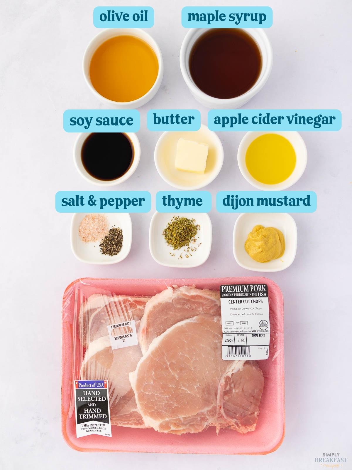 Image showing ingredients for a pork chop recipe. Includes olive oil, maple syrup, soy sauce, butter, apple cider vinegar, salt and pepper, thyme, Dijon mustard, and packaged center cut pork chops on a white surface.