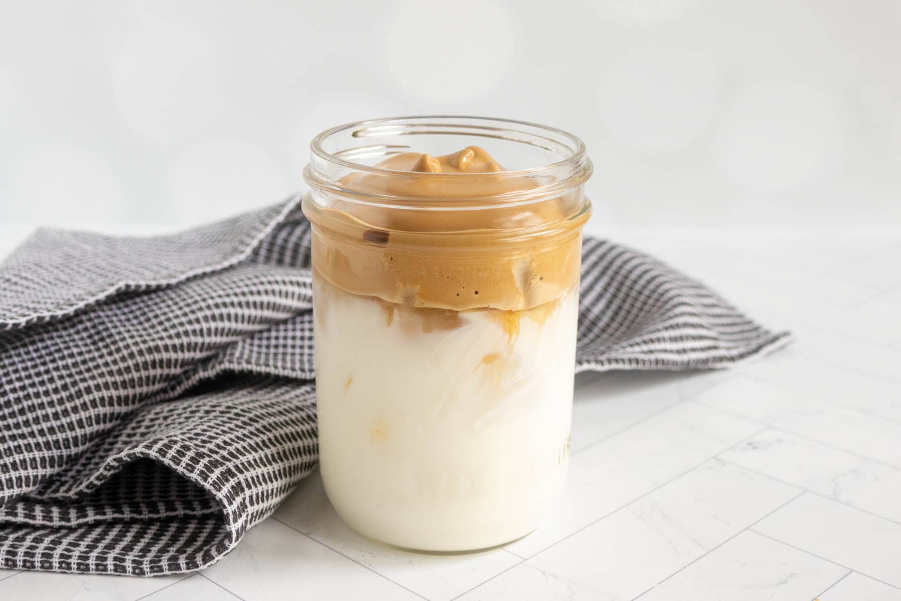 A glass jar filled with brown sugar whipped coffee and milk.
