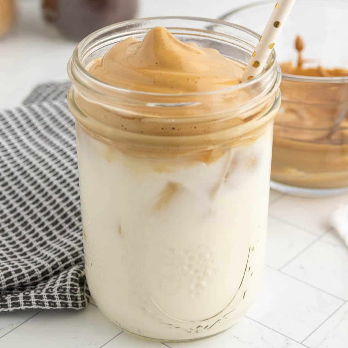A glass jar filled with whipped coffee and milk.