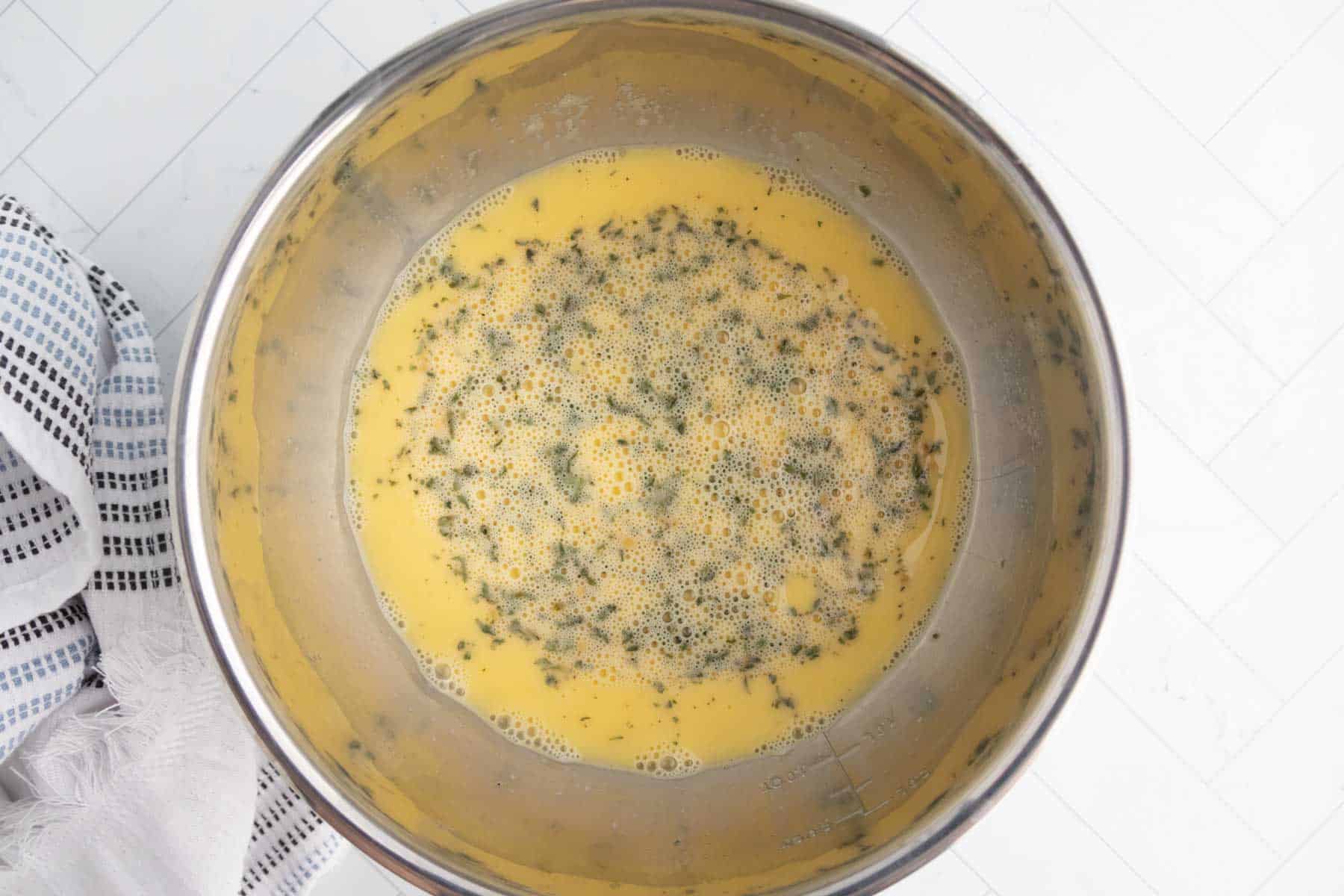 Whisked eggs with black pepper in a mixing bowl for breakfast recipes.