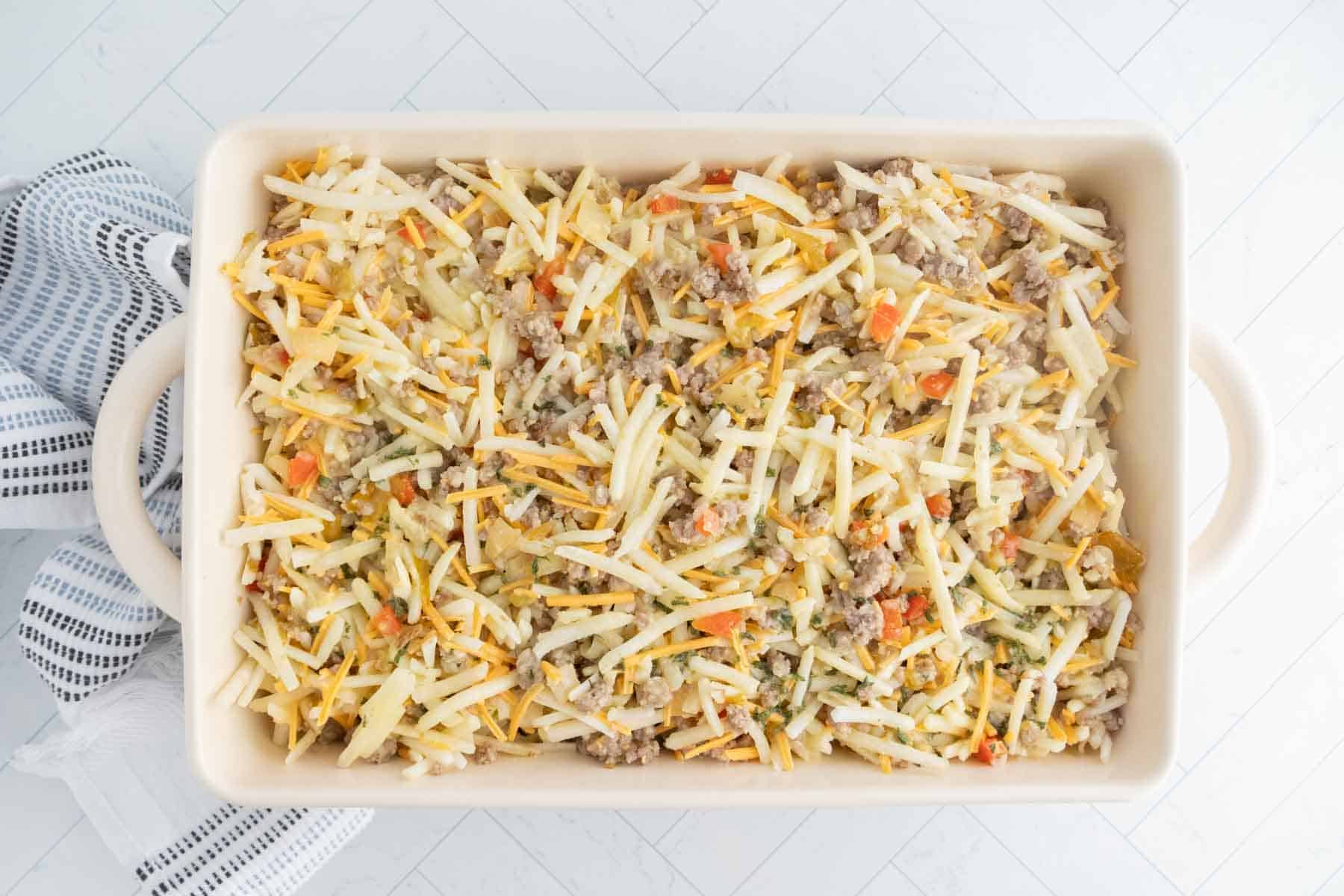 Creamy breakfast casserole with cheese, sausage, and vegetables in a baking dish.