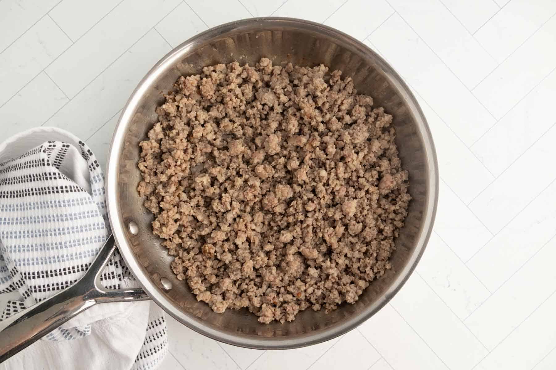 Ground beef in a stainless steel skillet for breakfast recipes.