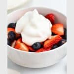 A bowl of strawberries and blueberries topped with a dollop of aquafaba whipped cream; text reads "aquafaba whipped cream, easy, vegan.