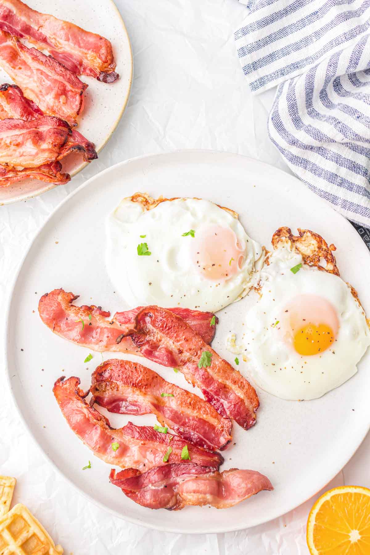 Slices of cooked bacon on a plate with two fried eggs.