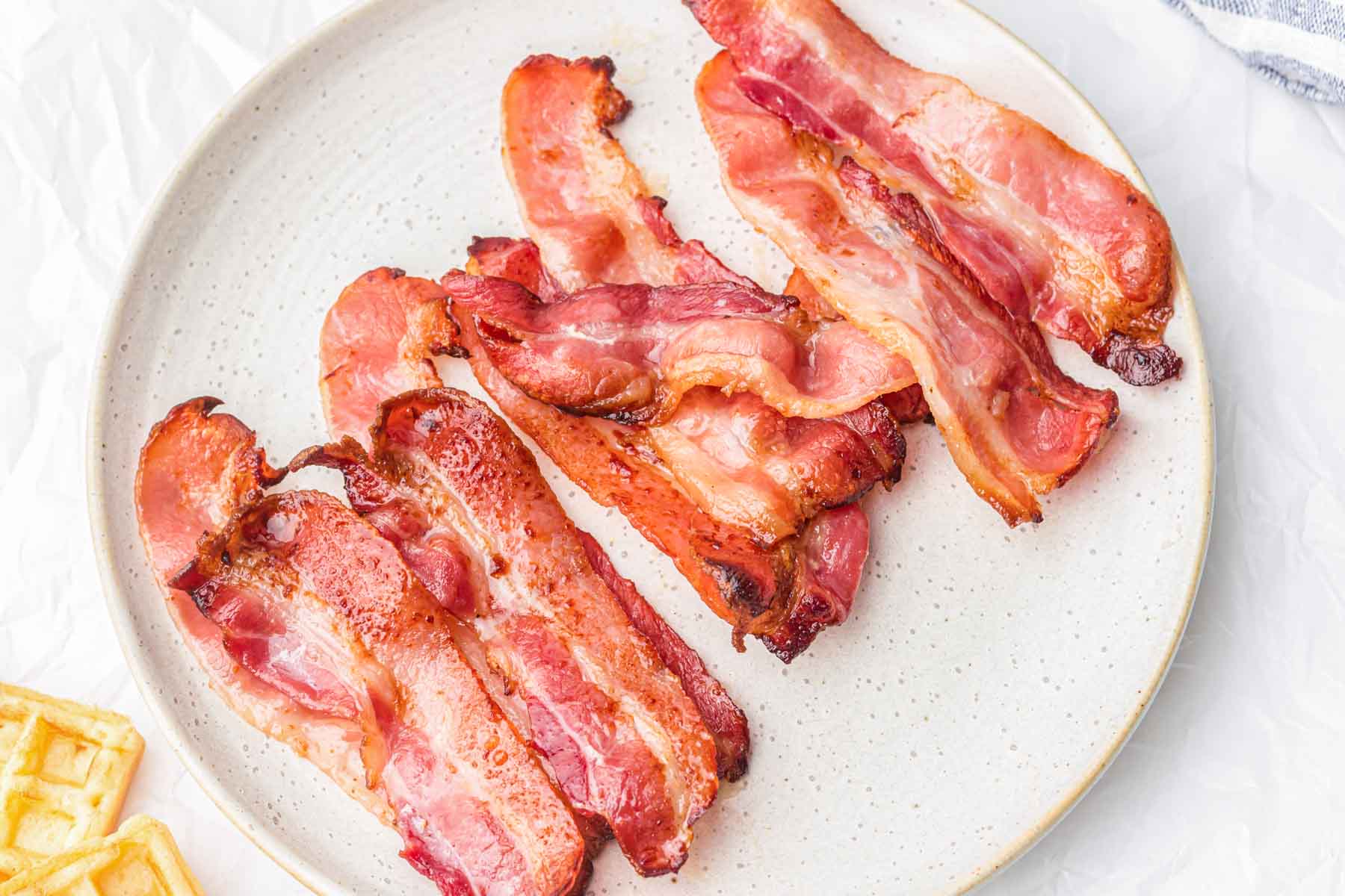Slices of cooked bacon on a plate.
