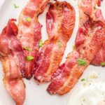 Cooked bacon on a plate with text overlay.