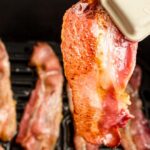 Tongs holding up a slice of bacon with text overlay.