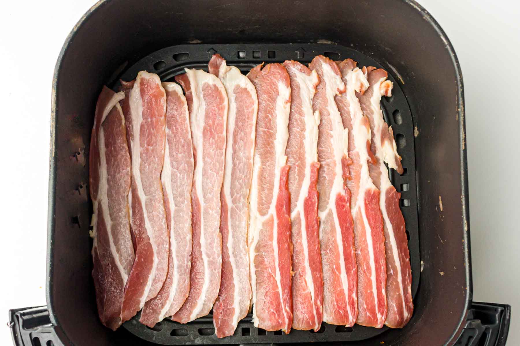 Uncooked bacon in an air fryer.