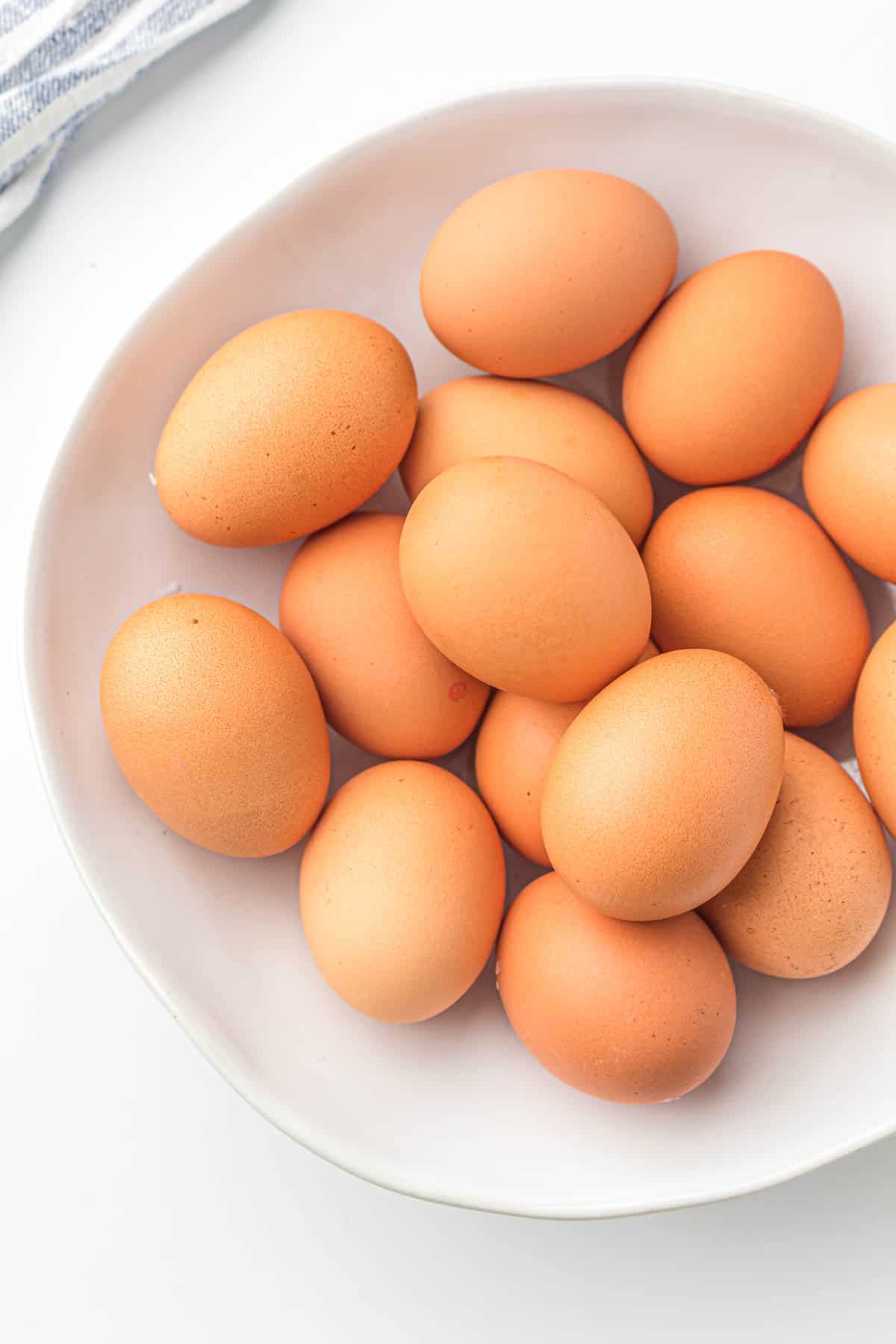 A white bowl filled with several brown eggs, viewed from above on a white surface—perfect for making air fryer hard boiled eggs.