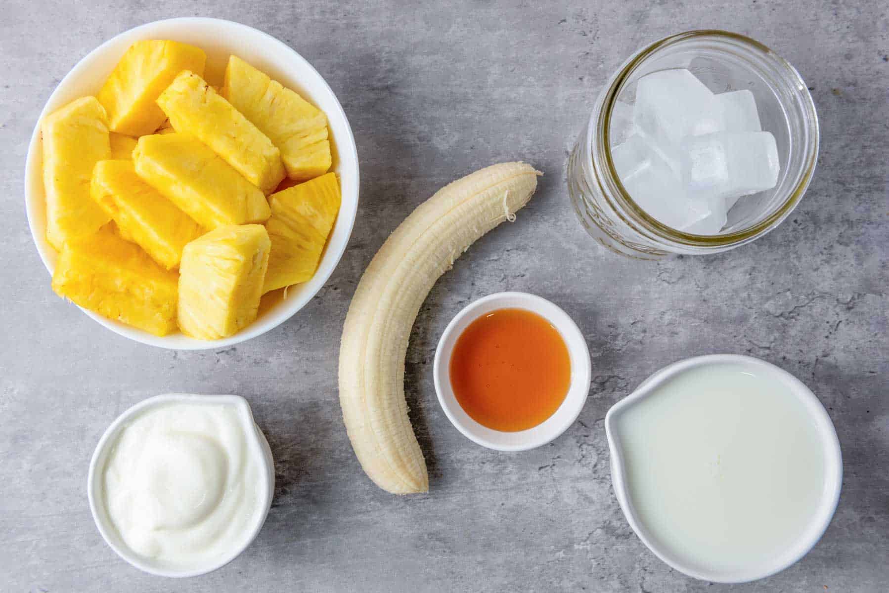 Ingredients for a pineapple smoothie on a stone countertop.